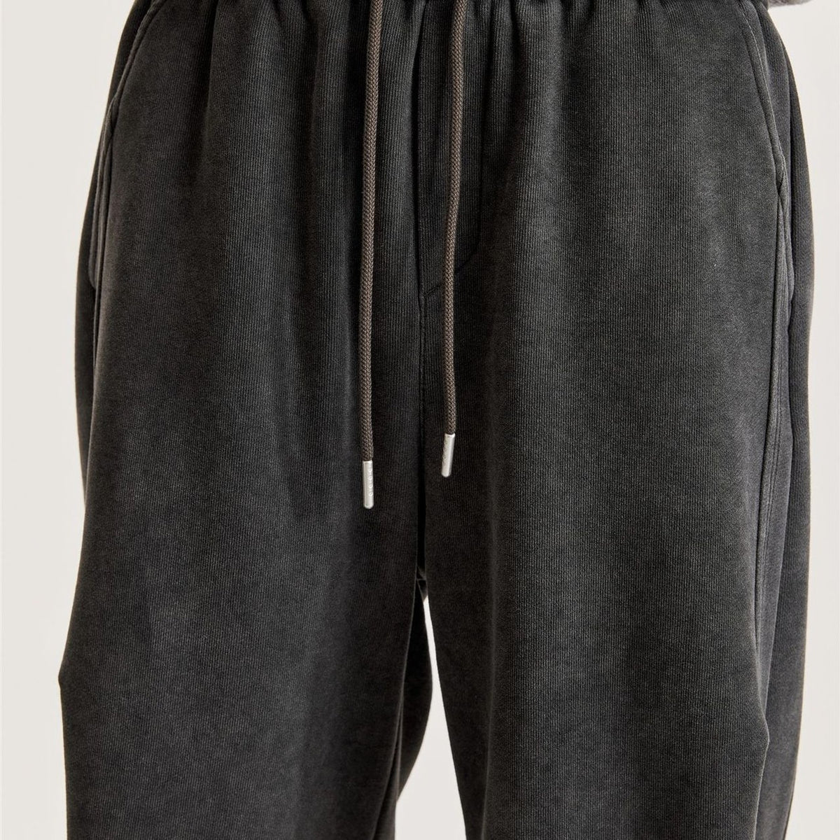 Front close-up of men's black wide-leg pants with elastic drawstring waist and metal cord tips