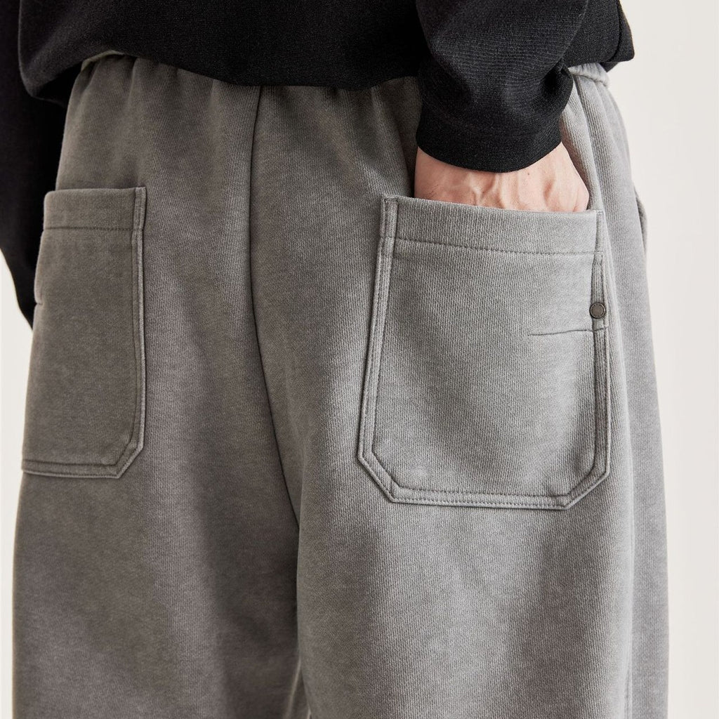 Back view of men's grey washed wide-leg pants with two patch back pockets and metal rivet detail